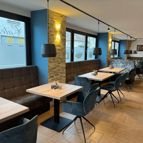 Ein modernes Café mit eleganten Holztischen und stilvollen Stühlen, die auf eine einladende Atmosphäre hinweisen.