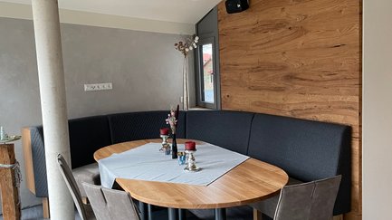 Flexible Sitzmöglichkeiten durch eine gepolsterte Bank und Stühle, ideal für geselliges Beisammensein in einem modern gestalteten Raum.