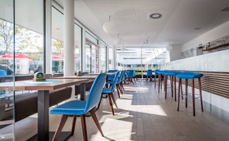 Die Inneneinrichtung des Lokals zeigt elegante Tische und Stühle, ergänzt durch eine offene Bar, die zur Geselligkeit einlädt.