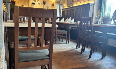 Ein gemütliches Restaurant mit Holztischen und Stühlen, das eine warme Atmosphäre durch die Ziegeldecke ausstrahlt.
