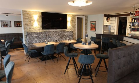 Elegante Restaurant-Einrichtung mit bequemen Stühlen und stilvollem Holzfußboden, ideal für geselliges Beisammensein.