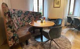 Die gepolsterte Rundbank mit buntem Blumenmuster ergänzt den runden Holztisch im gemütlichen Essbereich.