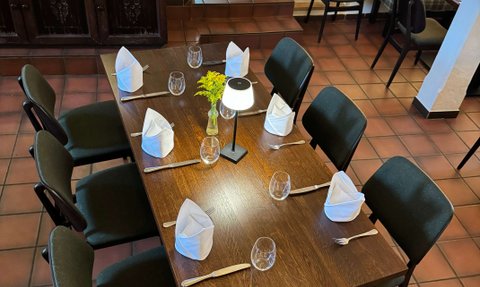 Ein einladend gedeckter Tisch mit stilvollen Stühlen, bereit für die nächste Mahlzeit, umgeben von gedämpfter Beleuchtung.