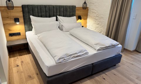 Ein modernes Schlafzimmer mit einem großen, gepolsterten Bett und eleganten Holzdetails an der Wand.
