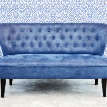 Blaue Sitzbank vor hellblauer Wand