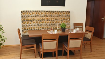 Ein eleganter Restaurantbereich mit einem Holztisch, umgeben von vier Stühlen und einer gemütlichen hohen Polsterbank.
