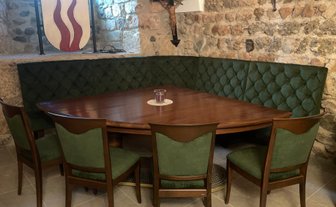 In einem einladenden Raum finden sich ein ovaler Tisch und gepolsterte grüne Sitzgelegenheiten in einer gemütlichen Ecke.