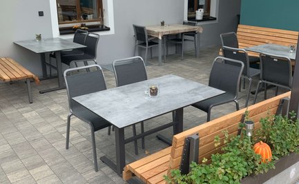 Gemütlicher Außenbereich mit Holz- und Metallmöbeln, der eine angenehme Atmosphäre für Gäste schafft.