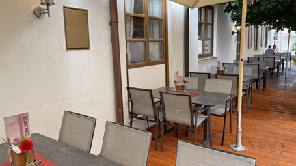 Ein einladender Außenbereich eines Cafés mit modernen Tischen und Stühlen.