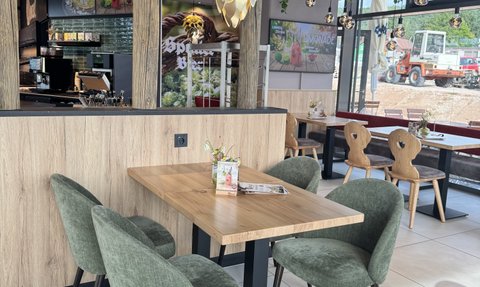 Der Innenraum eines Cafés zeigt einen eleganten Tisch mit einer kleinen Blumendekoration und einem auffälligen Lampendesign über dem Tisch.