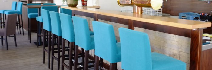 Türkisfarbene Hochstühle vor einer Holzbar