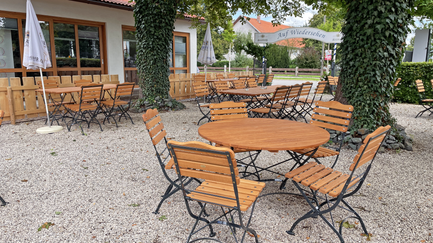 Eine gemütliche Terrasse mit Holzmöbeln und einem schattenspendenden Baum, ideal für entspannte Nachmittage.