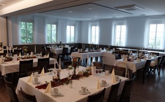 Helles, freundliches Ambiente mit schön eingedeckten Tischen, ideal für eine Feier oder Veranstaltung.