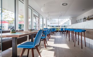 Die Inneneinrichtung des Lokals zeigt elegante Tische und Stühle, ergänzt durch eine offene Bar, die zur Geselligkeit einlädt.