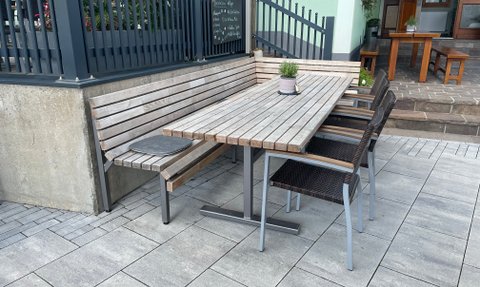 Ein gut gestalteter Außenbereich mit einem Holztisch und stilvollen Stühlen lädt zum Entspannen ein.