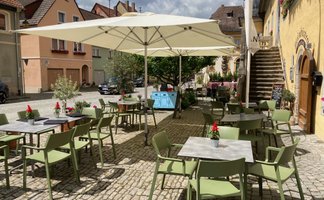 Eine charmante Atmosphäre auf einem gepflasterten Platz mit Stühlen und Tischen, bereit für ein geselliges Beisammensein.