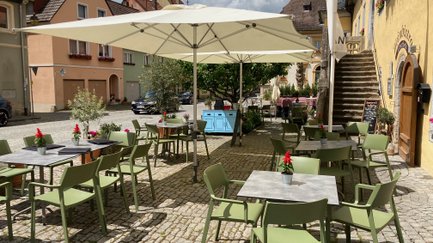 Eine charmante Atmosphäre auf einem gepflasterten Platz mit Stühlen und Tischen, bereit für ein geselliges Beisammensein.
