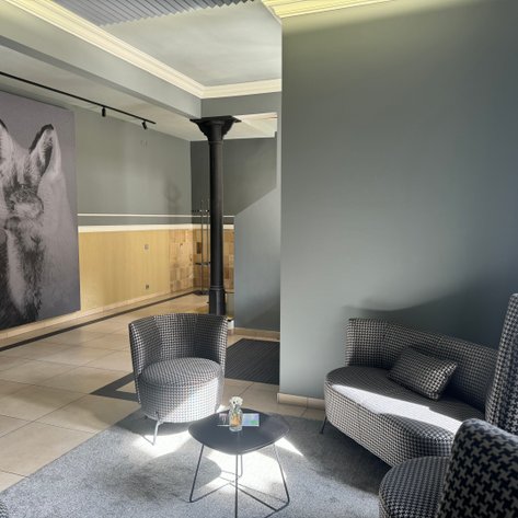 Ein eleganter Lounge-Bereich mit modernen Sesseln und einem großflächigen Kunstwerk eines Fuchses an der Wand.