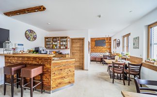 Eine entspannende Café-Szene mit einem rustikalen Stil, Holzdetails und großen Fenstern, die Tageslicht hereinlassen.