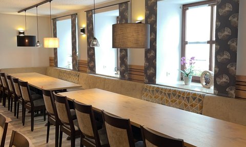 Ein stilvoll gestalteter Raum mit langen Holztischen und eleganten Stühlen, ideal für gesellige Zusammenkünfte oder Veranstaltungen.