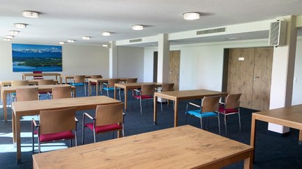 Ein moderner Besprechungsraum mit gut beleuchteten Tischen und bequemen Stühlen, der zur kreativen Zusammenarbeit einlädt.