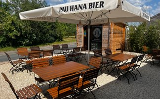 Ein gemütlicher Biergarten mit rustikalen Holzmöbeln und Sonnenschirmen bietet Platz für zahlreiche Gäste.