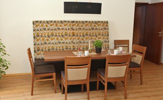 Ein eleganter Restaurantbereich mit einem Holztisch, umgeben von vier Stühlen und einer gemütlichen hohen Polsterbank.