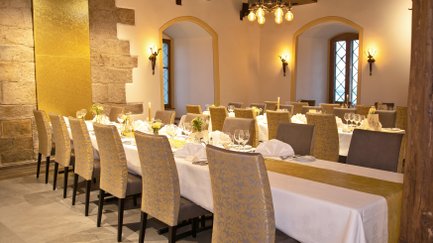 Im Rittersaal erstrahlen gedeckte Tische in warmem Licht, bereit für ein festliches Dinner mit stilvollem Ambiente.