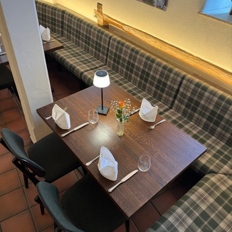 Die gemütliche Atmosphäre des Restaurants wird durch gepolsterte Bänke und das warme Licht am Tisch verstärkt.