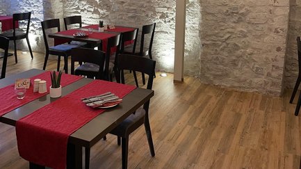 Schwarze Holztische mit roter Tischdecke und Holzstühle in einem Restaurant.