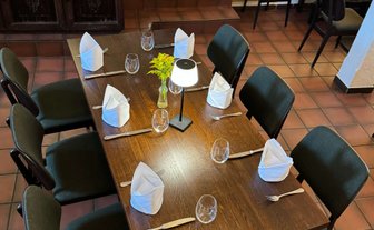 Ein einladend gedeckter Tisch mit stilvollen Stühlen, bereit für die nächste Mahlzeit, umgeben von gedämpfter Beleuchtung.