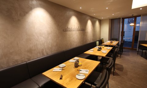 Beleuchteter Restaurantbereich mit gedeckten Tischen und gemütlichen Sitzbänken, ideal für gesellige Abende.