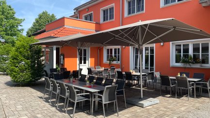 Gemütliche Terrasse eines Lokals, mit eleganten Stühlen und Tischen bereit für Gäste.