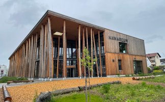 Die auffällige Fassade des Nawareum präsentiert sich mit Holzsäulen und einem begrünten Eingang.