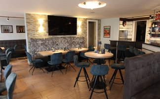 Elegante Restaurant-Einrichtung mit bequemen Stühlen und stilvollem Holzfußboden, ideal für geselliges Beisammensein.
