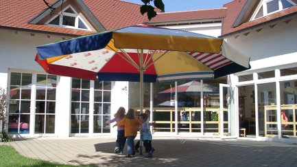 Kinder spielen an einem Schirm
