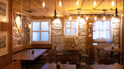 Ein gemütliches Restaurant mit Steinwänden, warmem Licht und rustikalen Möbeln, ideal für gesellige Abende.