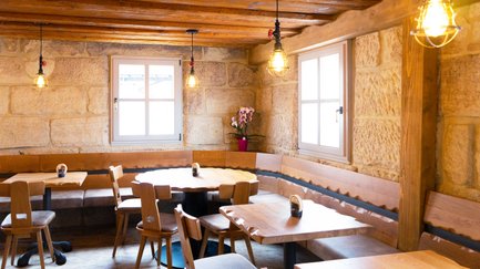 Eine gemütliche Restaurant-Ecke mit Holzstühlen und Tischen, die ein einladendes Ambiente schaffen.