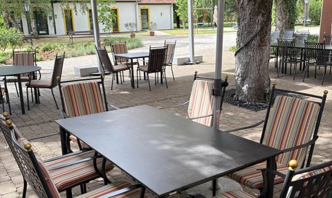 Gemütliche Terrasse mit eleganten Tischen und Stühlen, die auf einen sonnigen Tag in einem Restaurant hinweist.