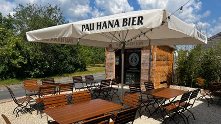 Ein gemütlicher Biergarten mit rustikalen Holzmöbeln und Sonnenschirmen bietet Platz für zahlreiche Gäste.