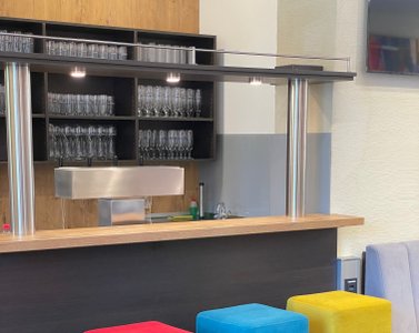 Bartheke mit Wandverkleidung und Barhockern in verschiedenen Farben