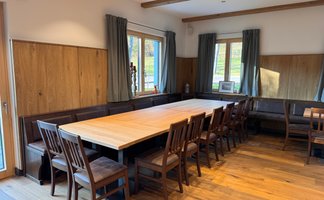Ein einladender Raum mit einem langen Holztisch und vielen Stühlen, ideal für gesellige Treffen oder Veranstaltungen.