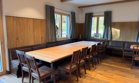 Ein einladender Raum mit einem langen Holztisch und vielen Stühlen, ideal für gesellige Treffen oder Veranstaltungen.