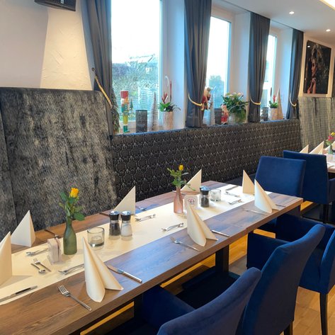 Das Restaurant zeigt eine stilvolle Inneneinrichtung mit grauen Wänden und sorgfältig platzierten Tischtüchern.