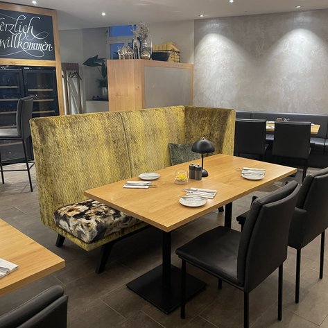 Ein stilvolles Restaurant mit modernen Möbeln, hellem Licht und einem einladenden Barbereich im Hintergrund.