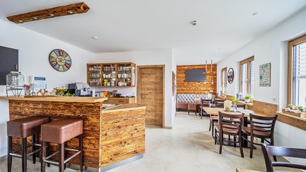 Eine entspannende Café-Szene mit einem rustikalen Stil, Holzdetails und großen Fenstern, die Tageslicht hereinlassen.
