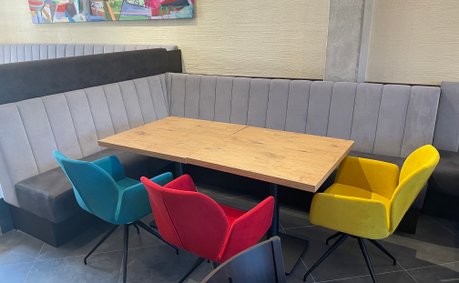 Ein türkiser, ein gelber und ein roter Sessel mit einer Eckbank und einem Holztisch