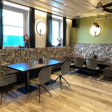 Ein gemütlicher Restaurantbereich mit dunkelbraunen Tischen und stilvollen Stühlen zu sehen.