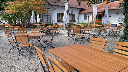 Eine gemütliche Terrasse mit Holzmöbeln und einem schattenspendenden Baum, ideal für entspannte Nachmittage.