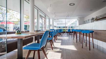 Die Inneneinrichtung des Lokals zeigt elegante Tische und Stühle, ergänzt durch eine offene Bar, die zur Geselligkeit einlädt.